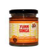A jar of Yumm Singa Laksa Curry Sauce with a bright orange label and red branding on a white background