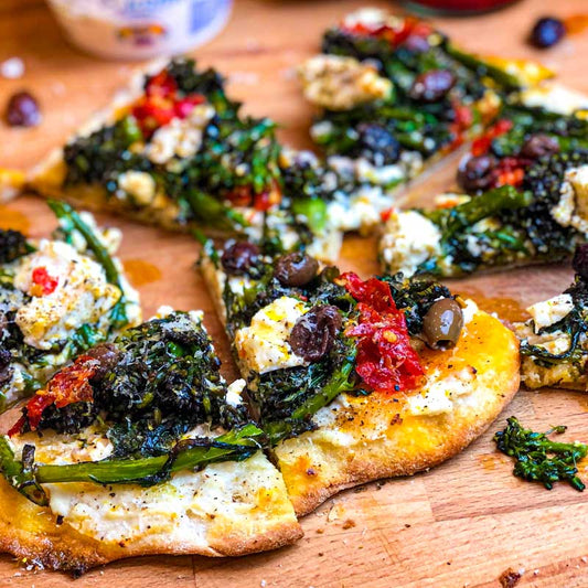 Cooked Pinsa Romana with Purple Sprouting Broccoli, ricotta and olives on a wooden board