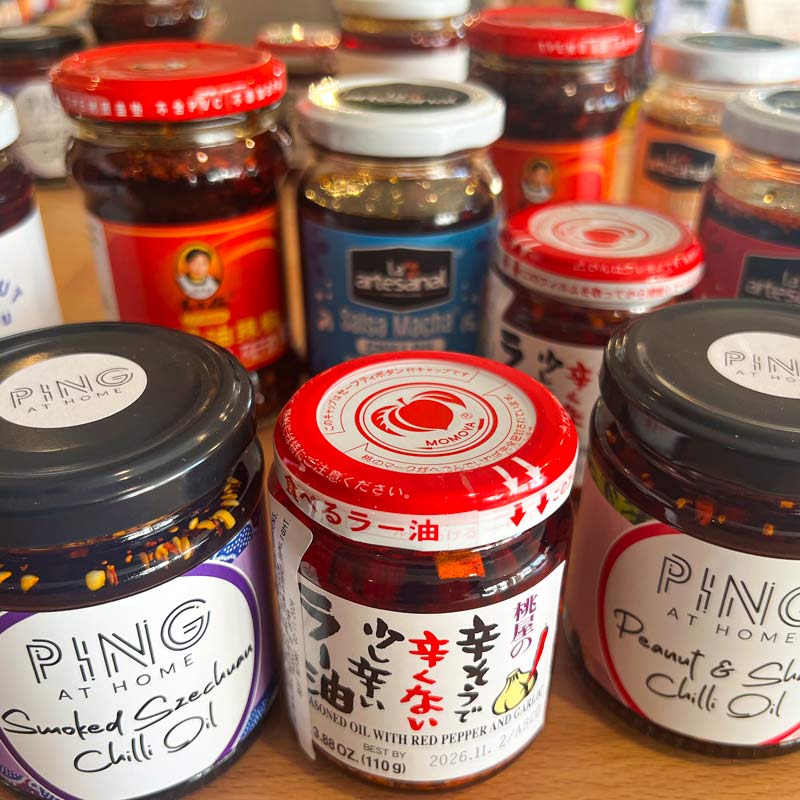 Assorted brands of crispy chilli oils on a wooden table