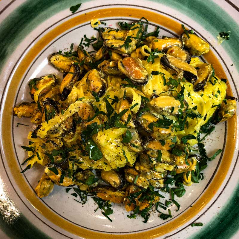 Recipe for Tagliatelle Pasta with mussels, saffron and cream on an orange and green plate