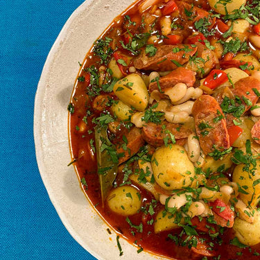 Recipe for Spanish Chorizo, white bean and potato stew, sprinkled with fresh parsley in a grey bowl